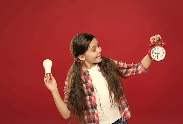 Tijd om inspiratie op te doen. klein meisje gloeilamp en klok. Bel het alarm en de lamp. brainstormen en tijdbeheer. Elektriciteit. Zakelijk idee. Tijd van verlichting. Idee en inspiratie — Stockfoto