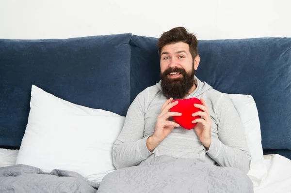 All you need is love. bearded man hold decoration heart in bed. heart full of love. start day with romantic. hipster with present. sweet heart. morning surprise from valentine. happy valentines day