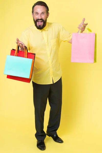 Zâmbește și continuă. Omul fericit ține saci de cumpărături fundal galben. Vânzarea sezonieră de autorizare. Vânzare și livrare. Îmbrăcăminte pentru bărbați la vânzare. Magazin de modă. Deoarece vânzarea sa, copiați spațiul — Fotografie, imagine de stoc