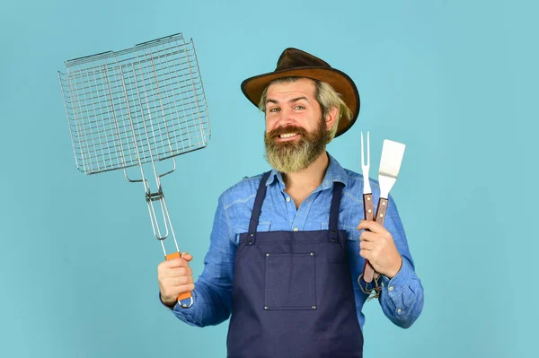 Penair picknick. Een man met een baard. Gereedschap voor het roosteren van vlees buiten. Picknick en barbecue. Klaar voor barbecue feestje. Culinair concept. Zomers weekend. gelukkig hipster hold kookgerei voor barbecue — Stockfoto