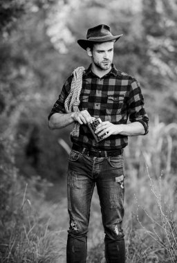 Vahşi Batı. Vahşi batı rodeosu. Şapkalı adam viski içiyor. Batı kovboy açık hava portresi. Kement ipli bir kovboy. Batı. Çiftlikte kareli gömlek. Klasik tarz adam. Vahşi Batı eski kovboy