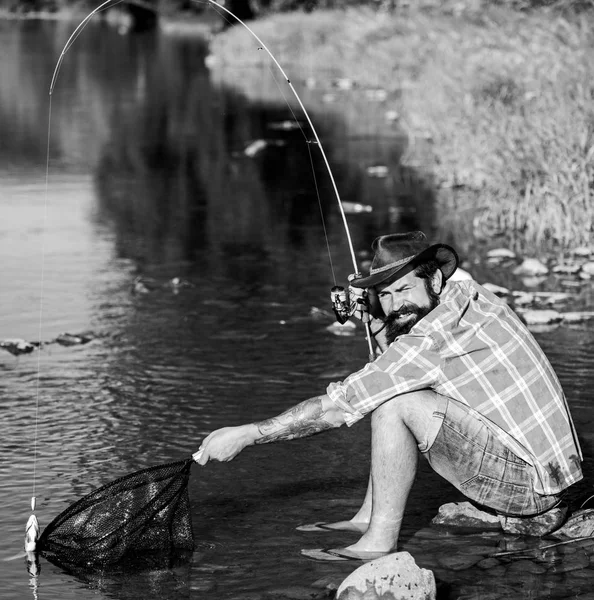 Casting that fish off. man with fish on rod. big game fishing. relax on nature. successful fisherman in lake water. hipster fishing with spoon-bait. fly fish hobby of man. Hipster in checkered shirt — Stock Photo, Image