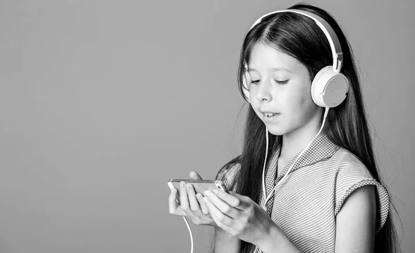 自己教育ですMP3プレーヤー。小さな女の子がヘッドフォンで子供はオンラインで勉強する電子ブックで学ぶ。家庭教育女の子は音楽を聞くオーディオブック。学校に戻って一生懸命勉強する。コピースペース — ストック写真