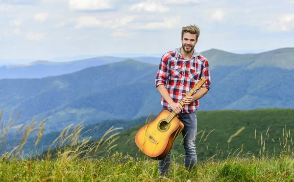 A hegyek csendje és a gitárhúr hangja. Hipszter zenész. Inspiráló környezet. Nyári zenei fesztivál a szabadban. Zenélni. Férfi zenész gitárral a hegy tetején. Inspirált zenész — Stock Fotó