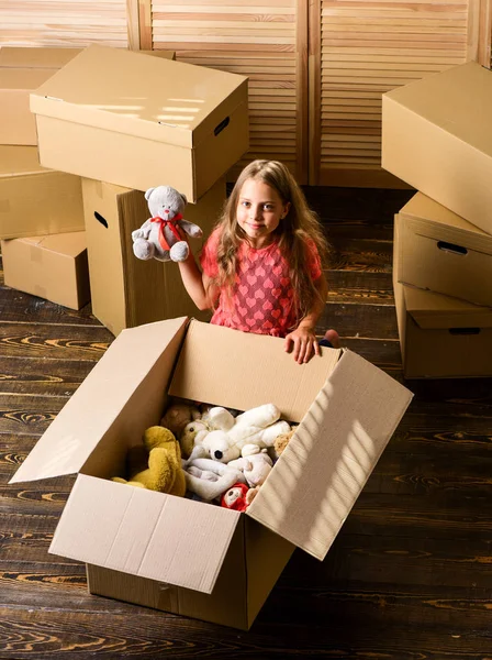 행복 한 어린이판지 상자. 행복 한 어린 소녀가 상자 위 방에 앉아 있습니다. 새로운 거 주지를 매입하는 것. 방을 수리한다. 새 아파트에 요. 움직이는 상자를 풀고. 판지 상자 - 새로운 집으로 이사하는 모습 — 스톡 사진