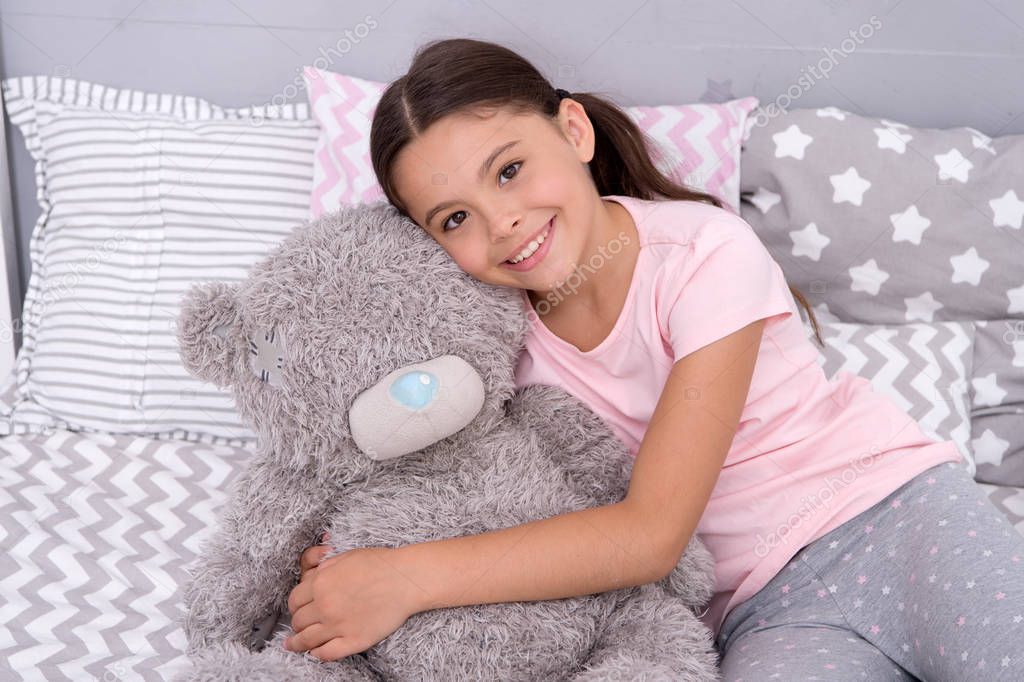 Kids evening routines. Favorite toy. Girl child hug teddy bear in her bedroom. Pleasant time in cozy bedroom. Girl kid long hair cute pajamas relax and play plush teddy bear toy. Pure love concept.