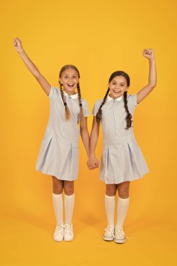 Güzel kız öğrenciler. Okul konseptine geri dönelim. Kuaför salonu. Sevimli kız öğrenciler. Örgülü saç stili olan kızlar. Neşeli kız öğrenciler sarı arka plan. Sevimli örgüler ile oynayan küçük kızlar