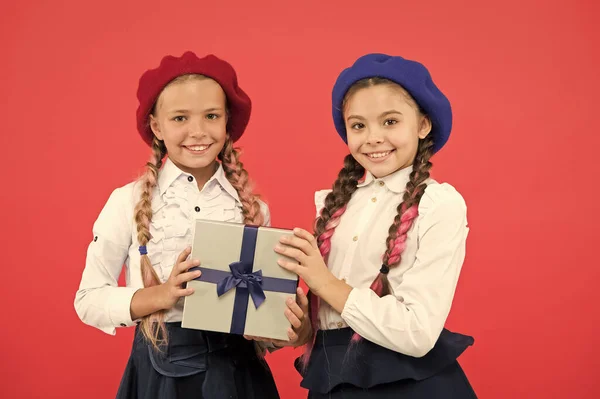 A barátság az igazi jelen. Kis gyerekek, akik születésnapi jelen rózsaszín háttér. Kislányok mosolyogva csomagolva jelen dobozban. Boldog gyerekek előkészítése iskola jelen szeptember 1. — Stock Fotó