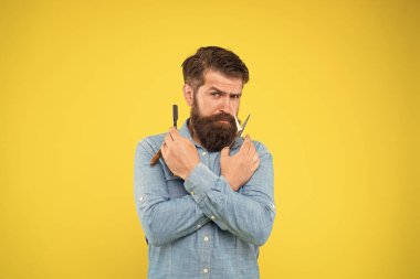 Gerçek bir bıçakla tıraş olmak kulağa hoş geliyor. Sakallı adam tıraş aletlerini sarı arka planda hazırla. Hippi, tıraş bıçağı ve makas tut. Usta berberden profesyonel tıraş. Berber dükkanı.