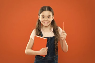 notlar yazma. çocuk günlüğü. okul kız turuncu arka plan kitap okuyun. dizüstü bilgisayar ile mutlu küçük kız. şiir ve roman. modern eğitim. edebiyat dersi. Okula geri dön. Sınavlara hazırlık