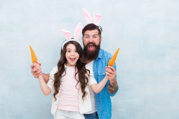 Tempo para vendas. família surpreso segurar cenoura. férias de primavera com a família. diversão festa em orelhas de lebre. a filha feliz e o pai celebram a Páscoa. Feliz Páscoa. menina usar engraçado coelho orelhas com o pai — Fotografia de Stock