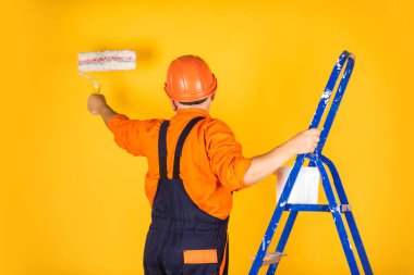 Foreman müfettişi. Kıdemli boyacı merdivende paten kullanır. Duvarı sarıya boyamak. İş kıyafetleri içinde profesyonel bir ressam. Odada duvar boyama işçisi. Tekerlekli erkek dekoratör