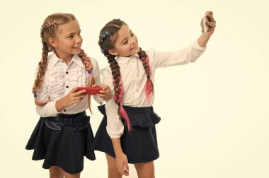 Blog kültürünüzü beslemek. Küçük okul çocukları beyaz izole yeni blog için selfie yapma. Küçük blogcular okul hayatı blog tutmak. Sevimli kızlar akıllı telefonlar ile blog fotoğrafları çekmek, kopyalama alanı