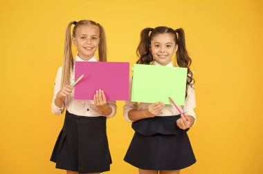 Okul reklamcılığına geri dönelim. Mutlu okul çocukları sarı arka plandaki boş çarşafları işaret ediyor. Yeni okul yılına başlayan küçük çocuklar. Küçük kızlar metin için boş okul posterleri tutan, kopya alanı