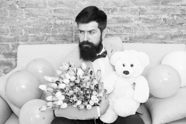 Flowers, anywhere anytime. Bearded man with tulip bouquet and bear. Love date. international holiday. Womens day. tulip flower for March 8. Spring gift. Bearded man hipster with tulip flowers. Tulips