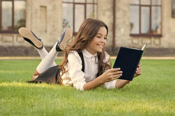 Always visit the library. Happy bookworm. Small child read library book on green grass. Adorable little girl borrow books from school library. Cute bibliopole. College bookstore. Library is fun