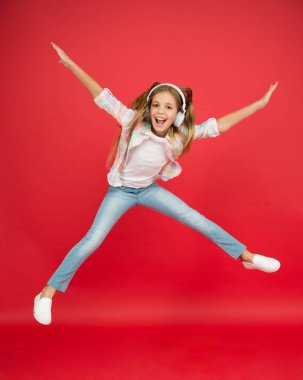 çocukluk mutluluğu. Mutlu çocuk müzik dinler. özgürlük ve başarı. Kulaklıklı küçük kız. Hayaline ulaş. Havada uçmak. Deliriyor. Heyecanlı küçük kız kulaklık takıyor. En sevdiğin şarkıyla dans et
