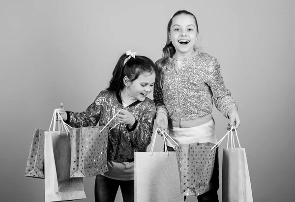 Día de compras. Los niños sostienen paquetes. Moda infantil. Espera más. Paga menos. Chicas hermanas amigas con bolsas de compras de fondo beige. Compras y compras. Viernes Negro. Venta y descuento —  Fotos de Stock