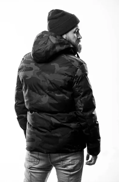 Hipster wintermode. Hij draagt een hoed en een zwarte winterjas. Comfortabele winterkleding. Winterse stijlvolle herenkleding. Man staan warme camouflage patroon jas parka met kap geïsoleerd op witte achtergrond — Stockfoto