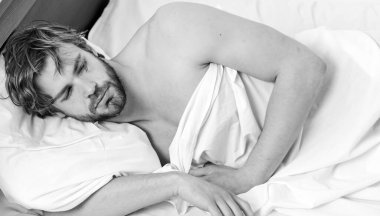 Yakışıklı adam esniyor ve kollarını kaldırıyor. Genç bir adam yatakta uyanıyor ve kollarını açıyor. Genç, yakışıklı adam tamamen dinlenmiş olarak uyanıyor..