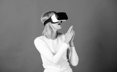 Şaşırmış genç bir kadın VR deneyimi sırasında havaya dokunuyor. Neşeli gülümseyen kadın VR gözlükleriyle bakıyor. 3D gözlük kullanan bir kadın heyecanlı. E sporu.