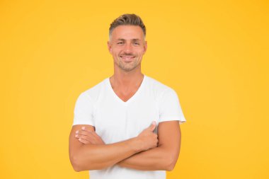 Kendinden emin ve iyimser. Kolları çapraz sarı olan kendine güvenen bir adam. Mutlu adam özgüvenle gülümser. Moda modelinin kendine güveni tam. Sıradan bir tarz. Erkek gardırobu. Kendinden emin ve mutlu.