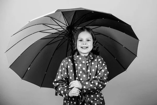 Fall season. Kid girl happy hold colorful rainbow umbrella. Rainy weather with proper garments. Rainy day fun. Happy walk under umbrella. There is rainbow always after the rain. Enjoy rain concept