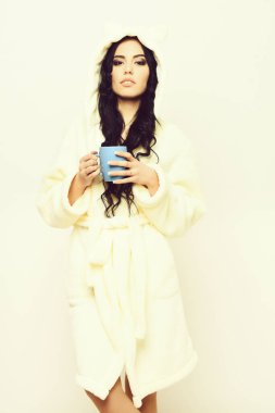 Fincanlı bej kadife bornozla poz veren seksi kız.