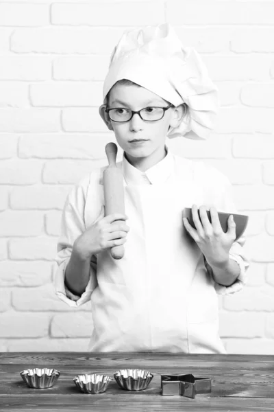 Tuğla duvarda aşçı aşçılığı yapan ciddi çocuk. — Stok fotoğraf