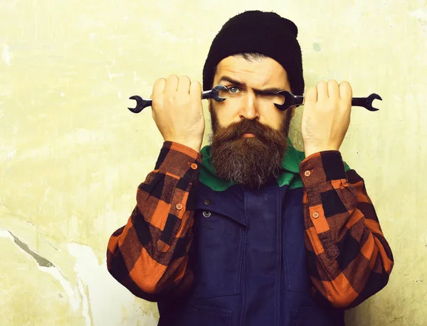 Bearded brutal caucasian mechanic holding metallic wrenches — Stock Photo, Image