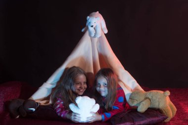 Childhood and leasure concept. Kids in pajamas covered with blanket