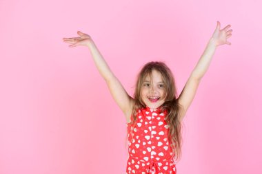 Girl smiling with raised hands on pink background