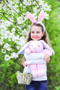 Easter holiday, little kid hug bunny. Spring and happy girl with pink ears.