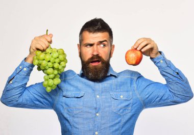 Bahçecilik ve bahçecilik konsepti. Adam üzüm ve elma tutuyor.