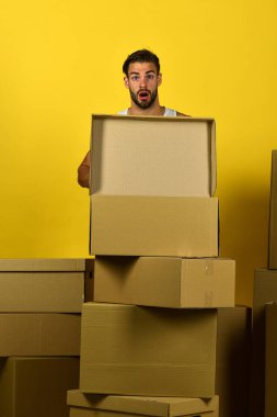 Sakallı, şaşkın suratlı, boş bir kutu tutan maço.