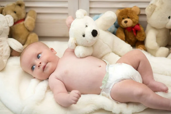Bambino sdraiato su piumone bianco. Bambino con orsacchiotto — Foto Stock