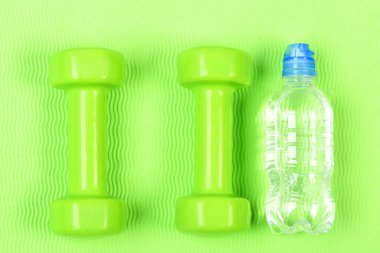 Spor, enerji ve diyet konsepti. Parlak arka planda el ağırlıkları ve su.