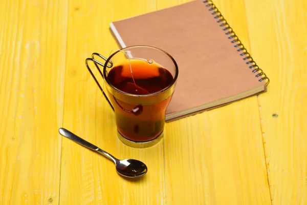 Склянка чорного чаю з мішком для чаю біля закритої книги — стокове фото