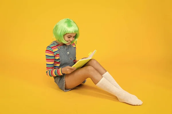 Chica friki leyendo la revista de cómics. Historietas de anime. Tienda de cómics. Abanico de anime. Niño alegre en peluca de colores brillantes. Concepto de fiesta Cosplay. Concepto de infancia feliz. Hobby y el interés. Lectura de literatura — Foto de Stock