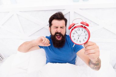 Erken kalkmanın sağlık yararları. Erken kalkmak daha fazla zaman kazandırır. Hippi sakallı adam çalar saati ile yatakta. Kalkma vakti. Sağlıklı alışkanlıklar. Harika bir günün başlangıcı. Her sabah erken kalkarım.