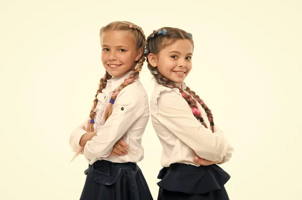 Lindo pero inteligente. Adorables niñas sonriendo aisladas en blanco. Chicas pequeñas y felices con uniforme escolar. Niñas de primaria con el pelo trenzado en trenzas largas. Adorables chicas orgullosas de ser compañeras de clase —  Fotos de Stock