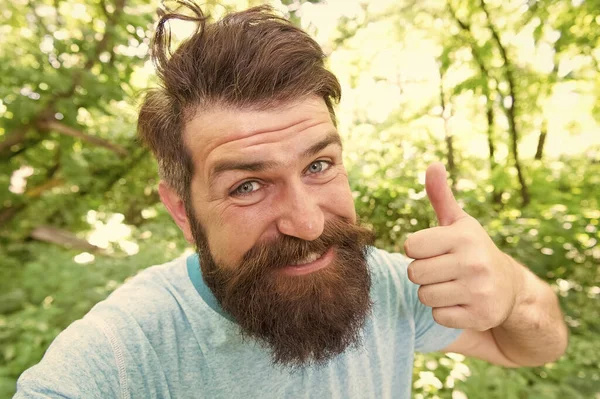 Comprimento de cabelo perfeito para sua forma de rosto. Homem feliz com cabelo estilizado dando como mão. Cara peluda com bigode elegante e barba cabelo na natureza verão. Hipster barbudo sorrindo com pêlos unshaven rosto — Fotografia de Stock