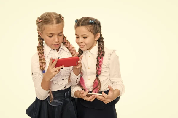 El futuro está aquí. Pequeñas colegialas utilizando teléfonos inteligentes aislados en blanco. Niños pequeños que aprenden tecnologías móviles para la vida futura. Carrera futura con habilidades digitales. El futuro de la educación, espacio de copia — Foto de Stock