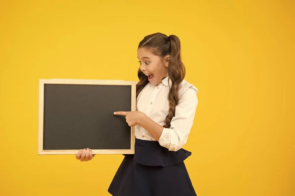 En bra publicitet för vår skola. Liten grabb pekande finger på tom svart tavla med skol publicitet. Litet barn som visar publicitet händelse på tidy tomma Chalkboard. Publicitet stiger ombord, kopierar utrymme — Stockfoto