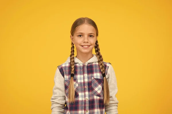 Ωραίο χαμόγελο. Hipster κορίτσι κίτρινο φόντο. Χαρούμενο σχολικό στυλ. Παιδική μόδα. Χαριτωμένα ξανθά μαλλιά. Παιδική ευτυχία. Χαρούμενη ημέρα των παιδιών. μικρό κορίτσι καρό σακάκι. Φθινοπωρινή — Φωτογραφία Αρχείου