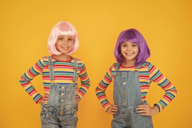 Life is better with friends. Happy girls friends on yellow background. Little friends smile in fashionable hair wigs and stylish overalls. Adorable small friends enjoy friendship. Playmates clipart
