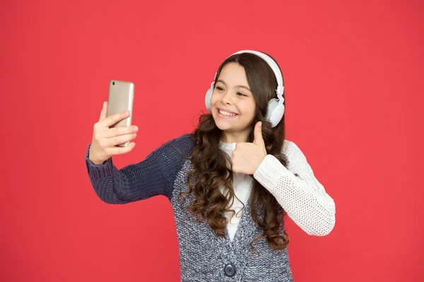 Tiempo de diversión selfie. Mi lista de reproducción es la mejor. Pequeña chica blogueando. concepto de la vida moderna. la felicidad infantil del chiquitín. Niño pequeño elegir la música en el teléfono inteligente. Niño pequeño usa auriculares tocando música — Foto de Stock