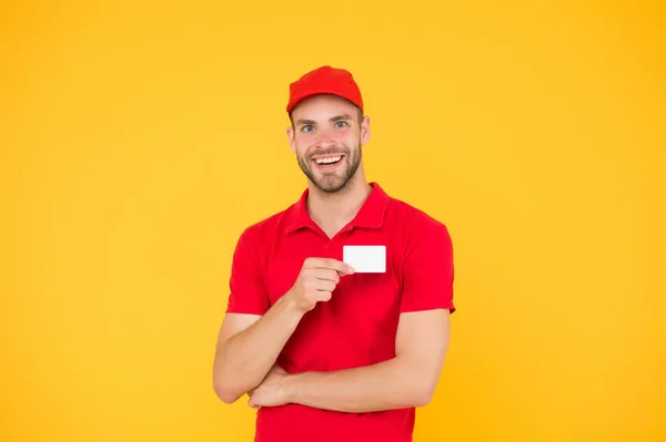 Feliz de servir. Hombre gorra roja fondo amarillo. Entregando compra. Entregado a su destino. Servicio de entrega. Mensajero y entrega. Repartidor de carteros. Tarjeta de descuento. Contacto comercial — Foto de Stock