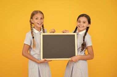 Okul haberleri. Gerçek bilgi. Küçük kızlar yazı yüzeyi sarı arka plan tutun. Bilgi için boş tahta. Taze okul bilgileri kopyalama alanı. Bilgi yazmak için çocuklar ve tebeşir tahtası