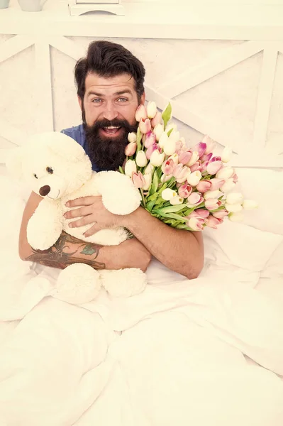 Thank you. love valentines day. womens day. flowers for march 8. good morning surprise. happiness about present. cheerful bearded man in bed. happy birthday gift. spring fresh tulip and bear toy